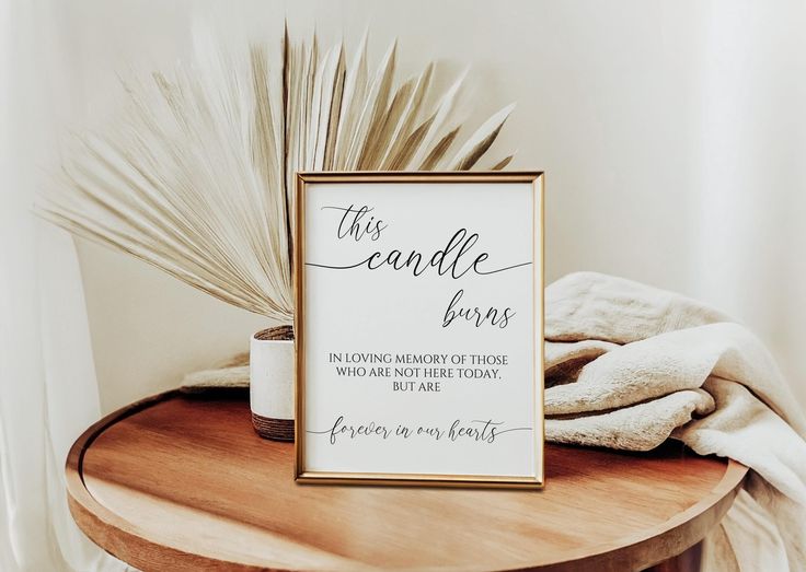 a wooden table topped with a framed sign and a white cup filled with coffee sitting on top of it