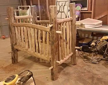 a wooden bed frame sitting on top of a floor next to a pile of tools