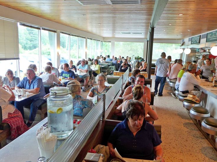 people sitting at tables in a restaurant with food on the counter and eating from bowls