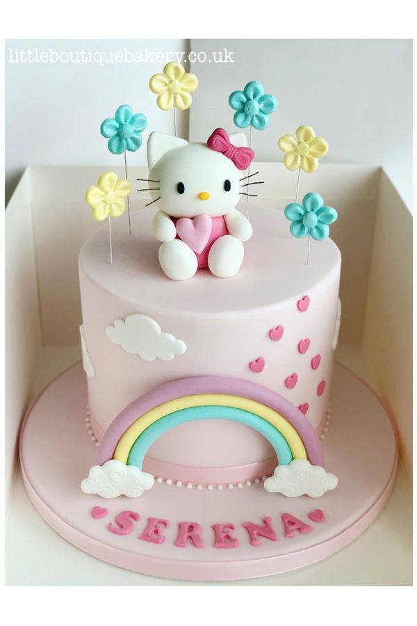 a hello kitty birthday cake with flowers and a rainbow on the top is ready to be eaten