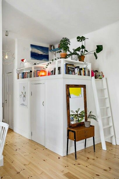 a living room with white walls and wooden flooring next to a bookshelf