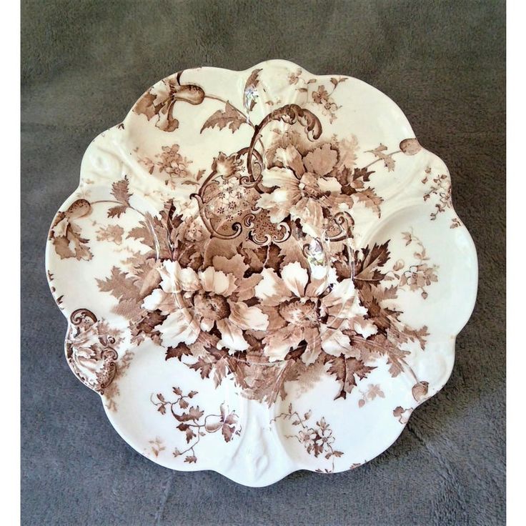 a plate with flowers on it sitting on a tablecloth covered floor next to a wall