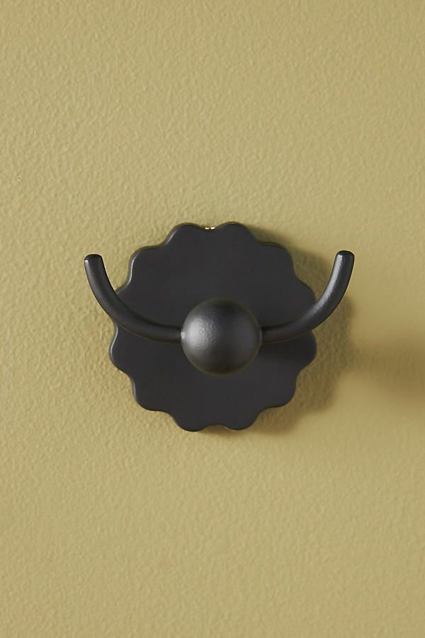 a black door handle on the side of a yellow wall with a silver ball in it