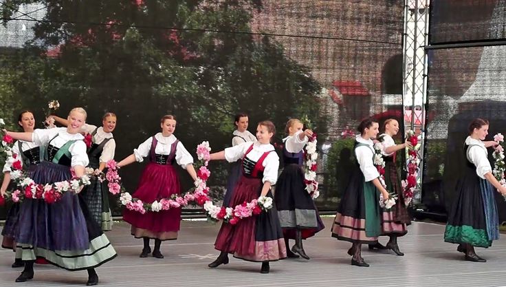 a group of people that are standing in the street with flowers on their heads and skirts