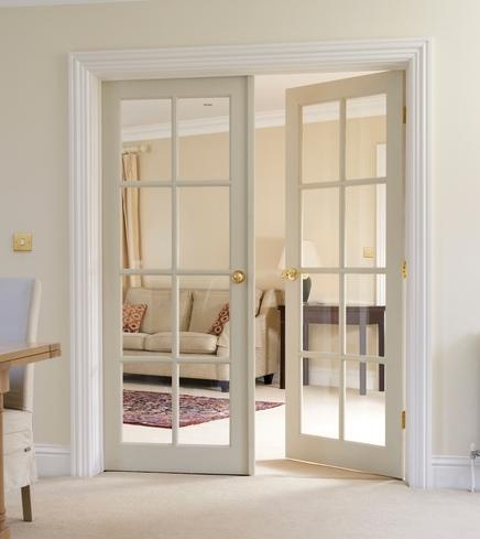 an open door leading to a living room with white furniture and beige carpeted flooring