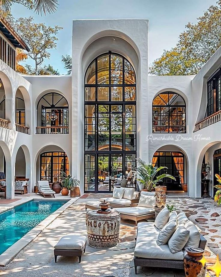 an outdoor living area with couches, chairs and a pool in front of it