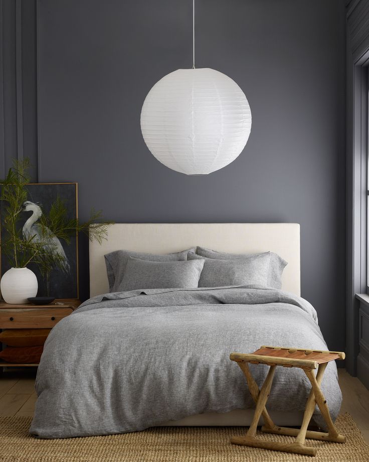 a bedroom with grey walls and white bedding