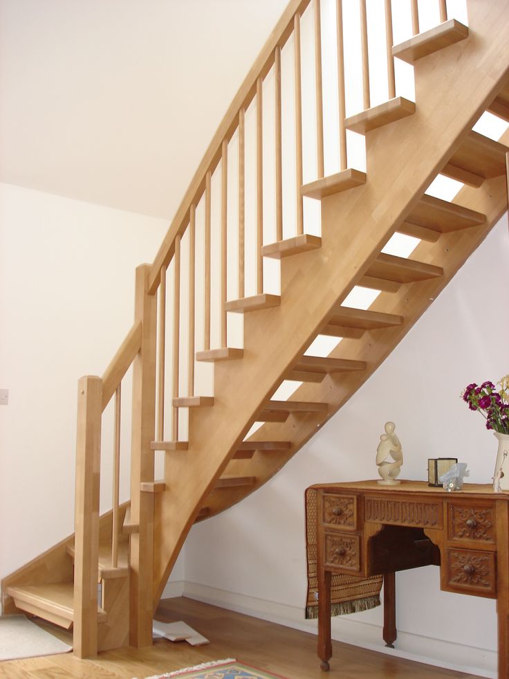 a wooden stair case next to a desk with flowers on it and a vase filled with purple flowers