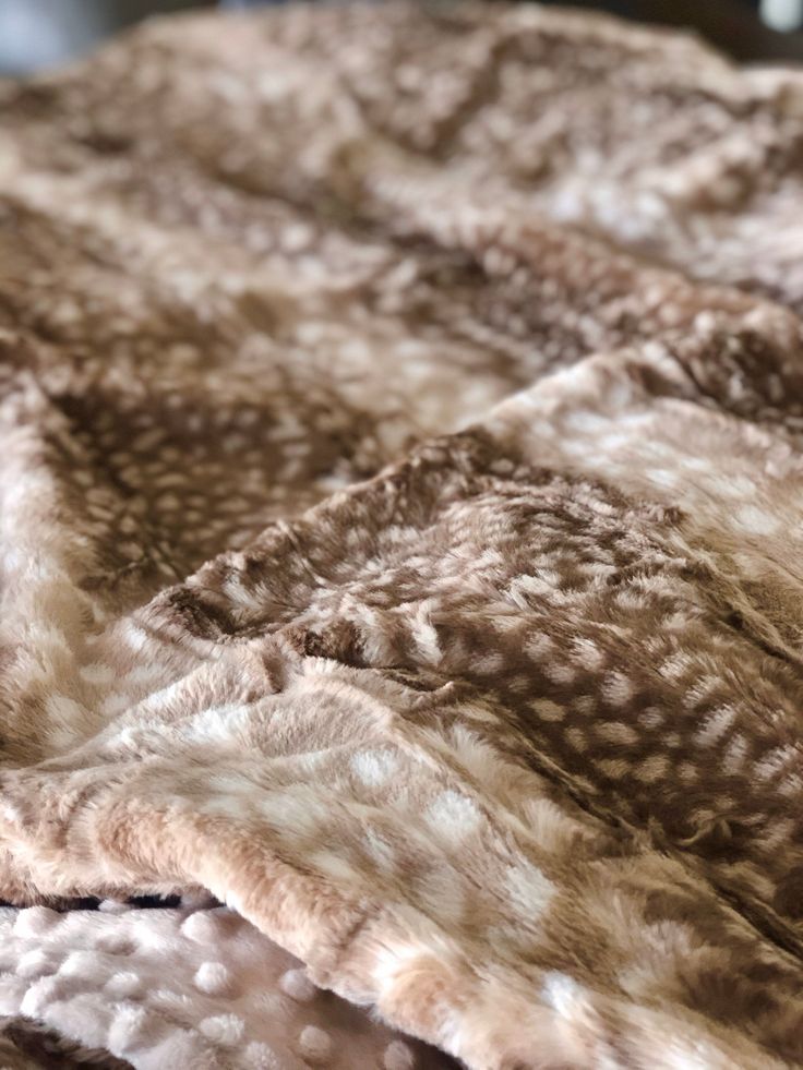 an animal print blanket is laying on top of a bed with brown and white fur