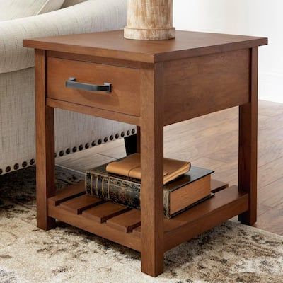 a wooden end table with books and a vase on it next to a white couch