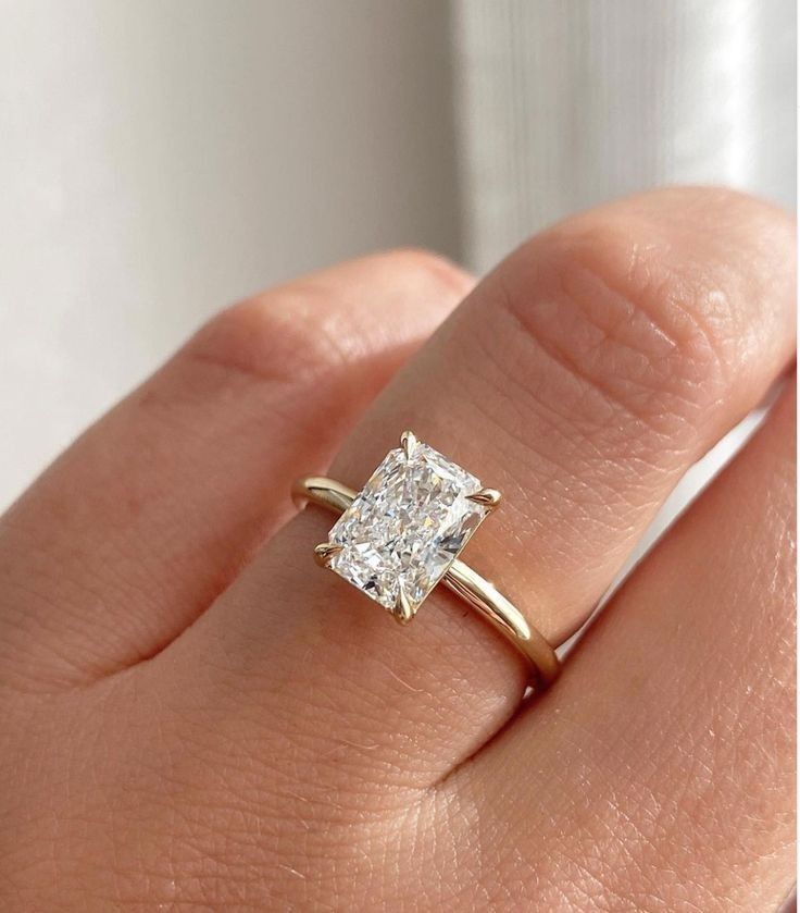 a woman's hand with a diamond ring on top of her finger and an engagement band