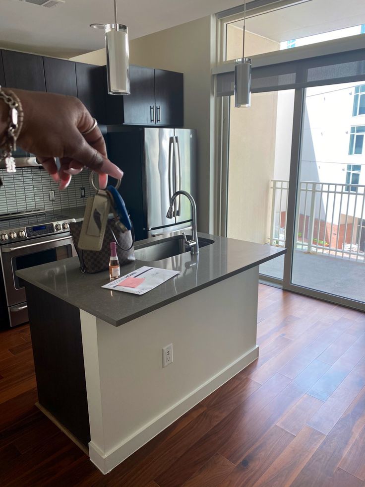 a person is reaching for something on the counter top in a kitchen with wood flooring