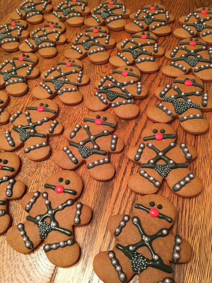 some very pretty decorated ginger cookies on a wooden table with red and green decorations around them