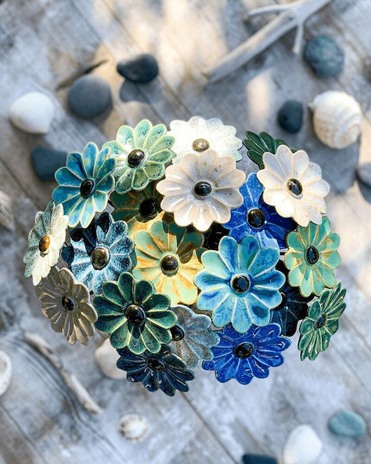 an arrangement of flowers sitting on top of a wooden table next to rocks and pebbles