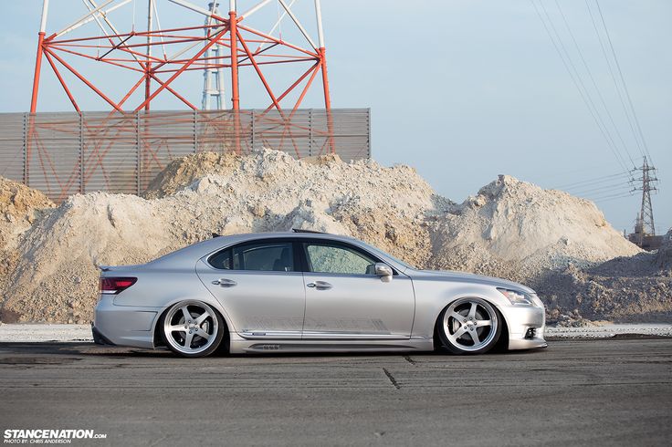 a silver car parked in front of a pile of dirt and power lines with a building in the background