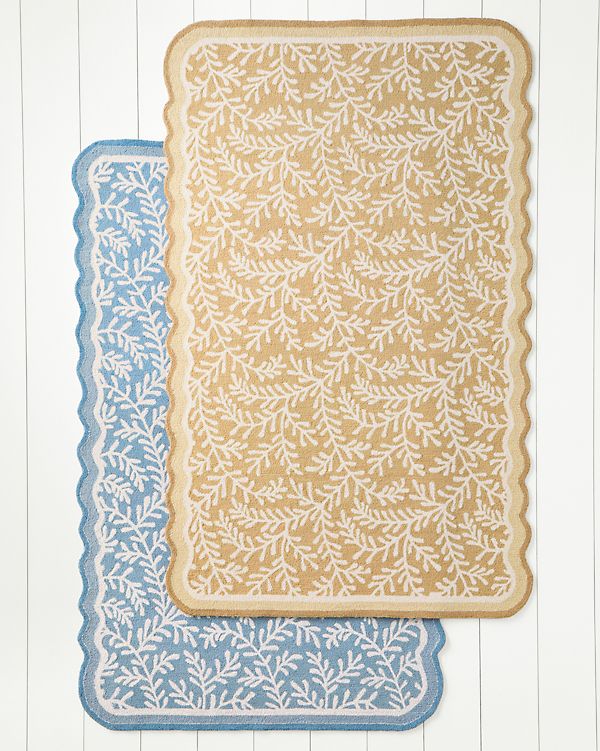 two blue and yellow placemats sitting on top of a white wooden table next to each other