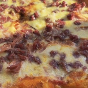 a close up view of a pizza with cheese and meat toppings on the top