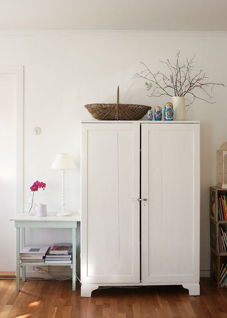 a white cabinet sitting on top of a hard wood floor next to a book shelf