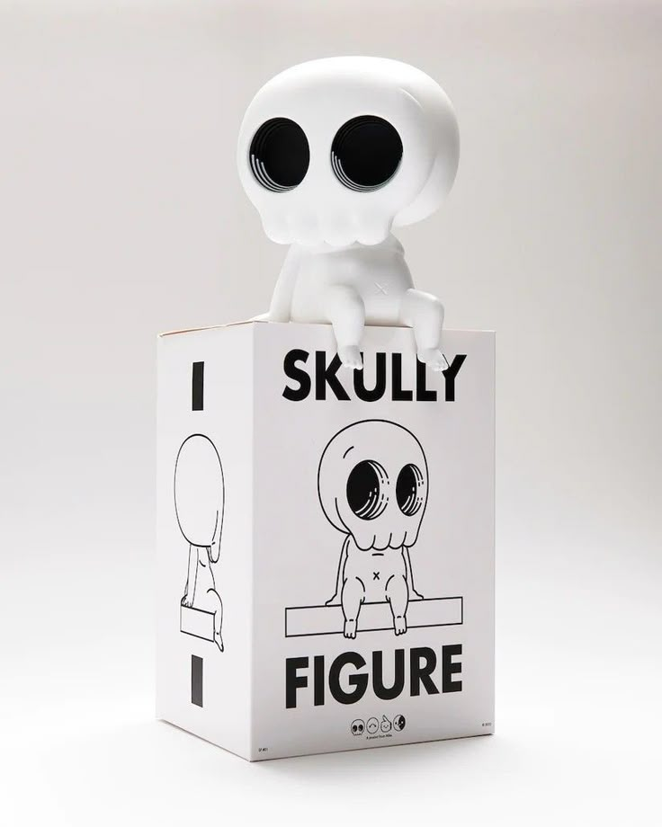 a white toy sitting on top of a box with black eyes and an alien face