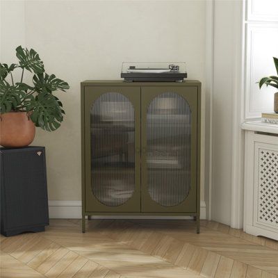 a green cabinet sitting next to a potted plant on top of a hard wood floor