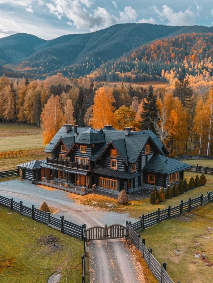 an aerial view of a large home surrounded by mountains and fall foliage in the background