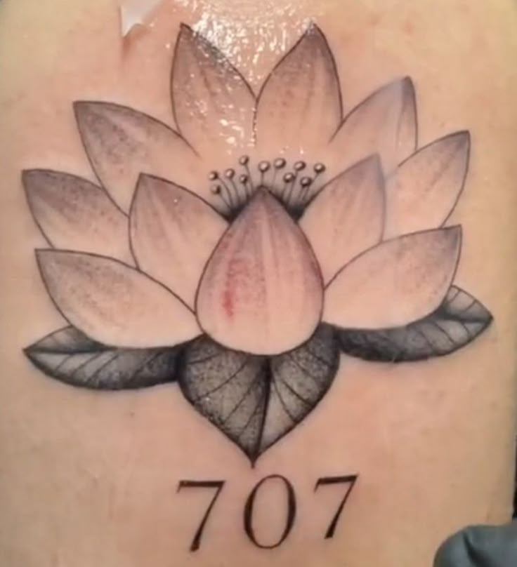 the back of a woman's shoulder with a lotus tattoo on it