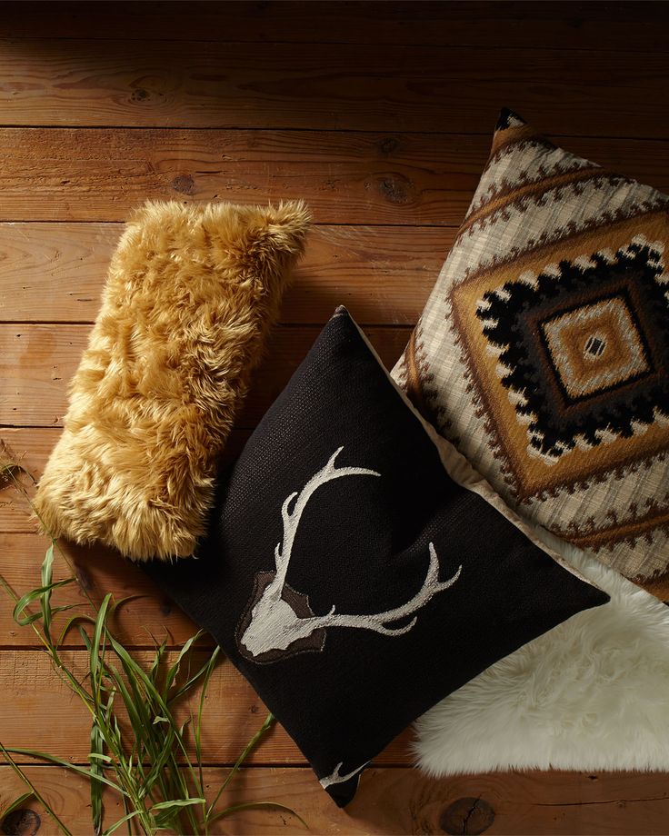 two pillows and a stuffed animal are on the floor next to each other, one with a deer's head painted on it