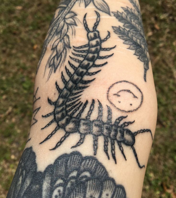 a person with a tattoo on their arm that has an image of a scorpion and other animals