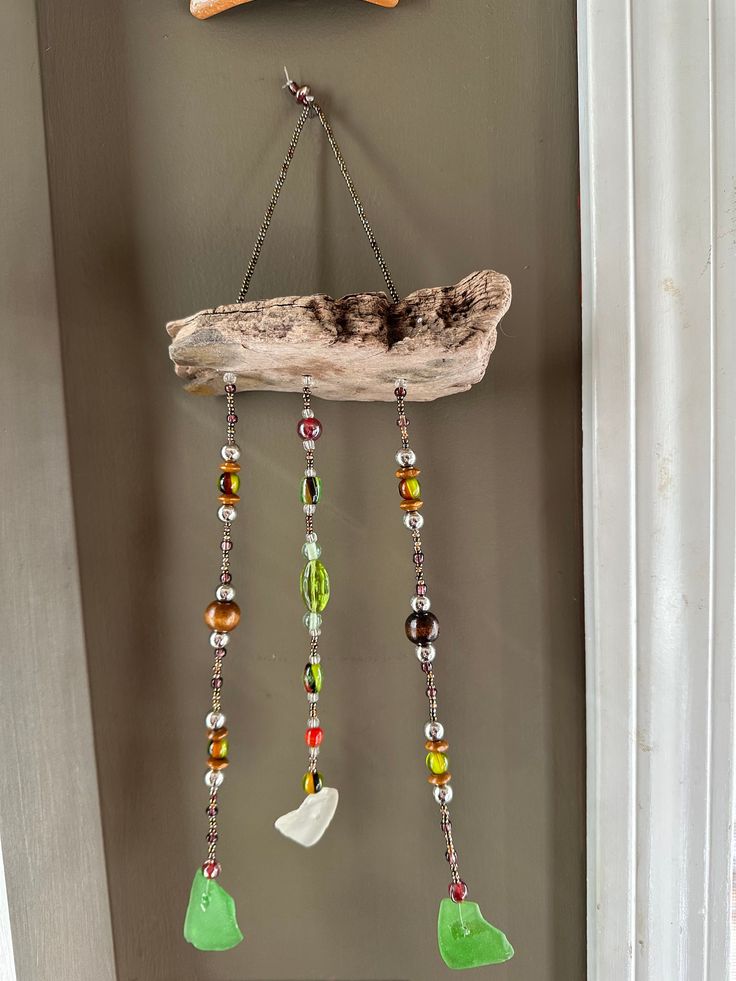 a piece of driftwood is hanging on the wall next to a glass beaded wind chime