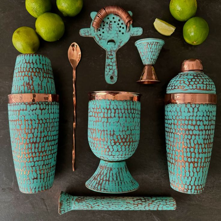 an assortment of teal and copper colored items including cups, utensils and limes