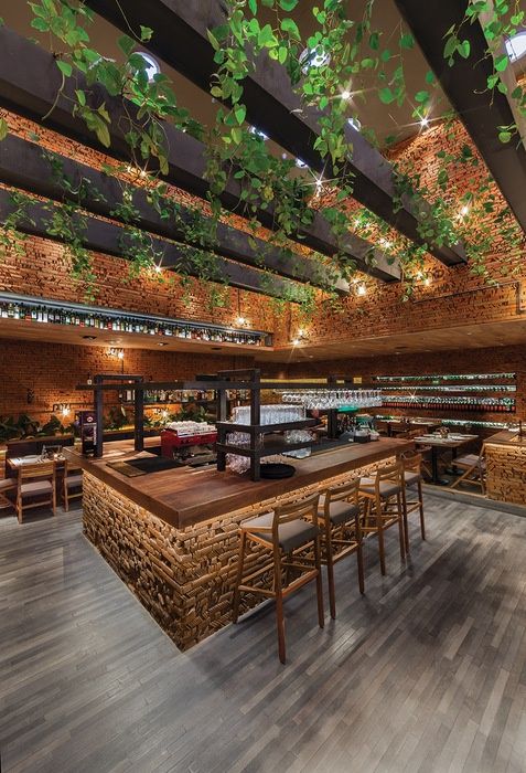 the interior of a restaurant with exposed brick walls and wooden tables, hanging plants on the ceiling