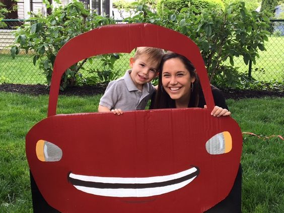 a woman and boy are posing in a cardboard car