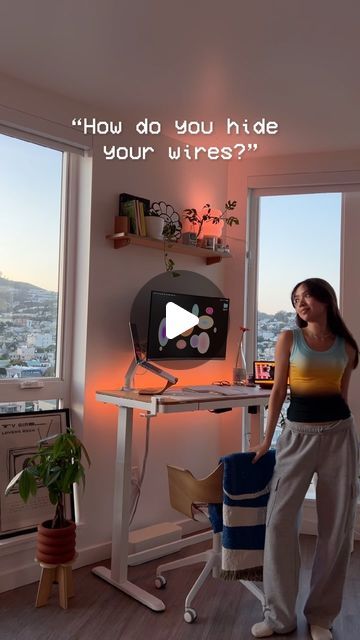 a woman standing in front of a desk with a monitor on it