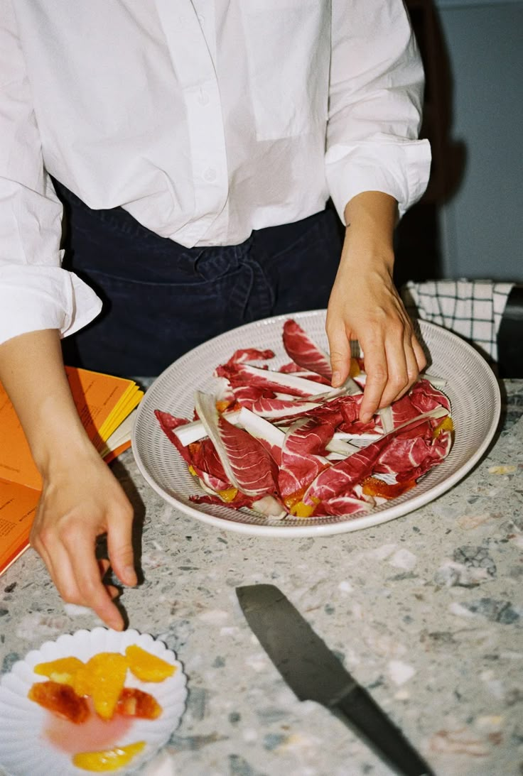 a woman is cutting up raw meat on a plate