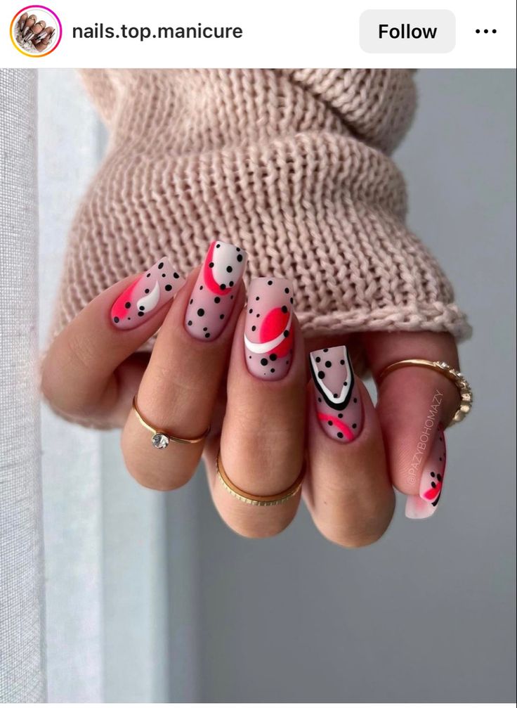 a woman's hand with pink and black polka dot nail art