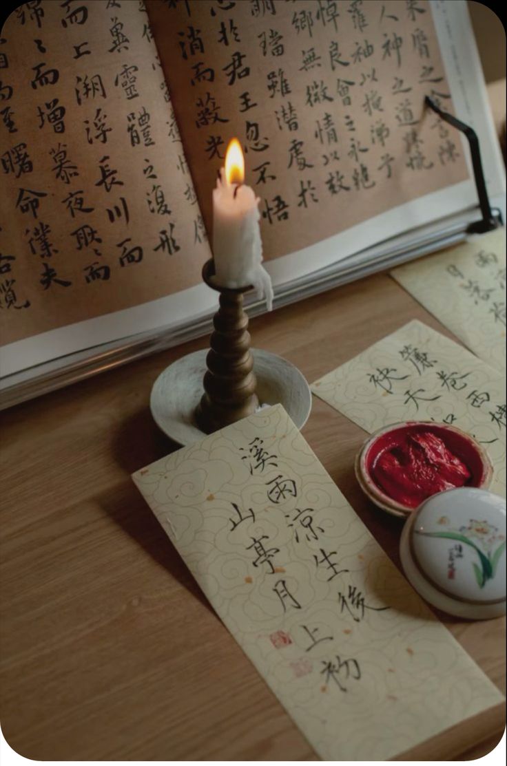 an open book with writing on it next to a lit candle and two small bowls