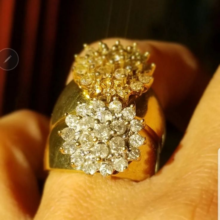 a close up of a person's hand holding a gold and diamond ring