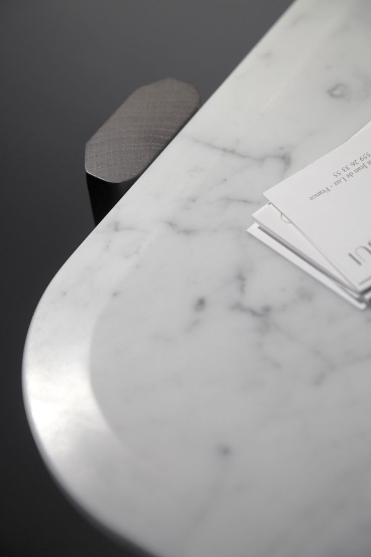 a close up of a white marble table with papers on it and an apple in the background