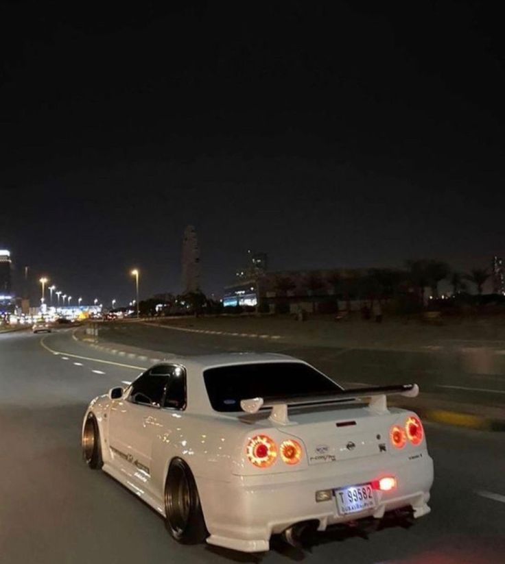 a white sports car driving down the road at night