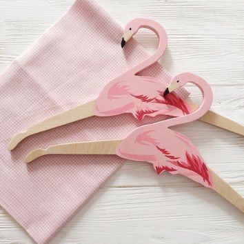 two pink flamingos sitting on top of a pink towel next to each other with wooden handles