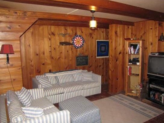 a living room with wood paneling and a television on the wall in front of it