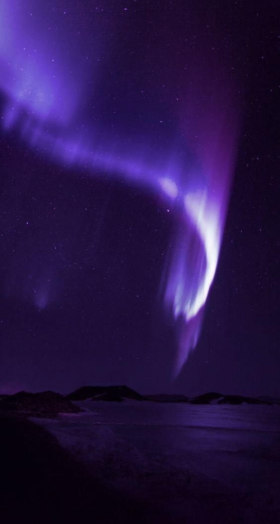 an aurora bore in the night sky with purple and green lights on it's side