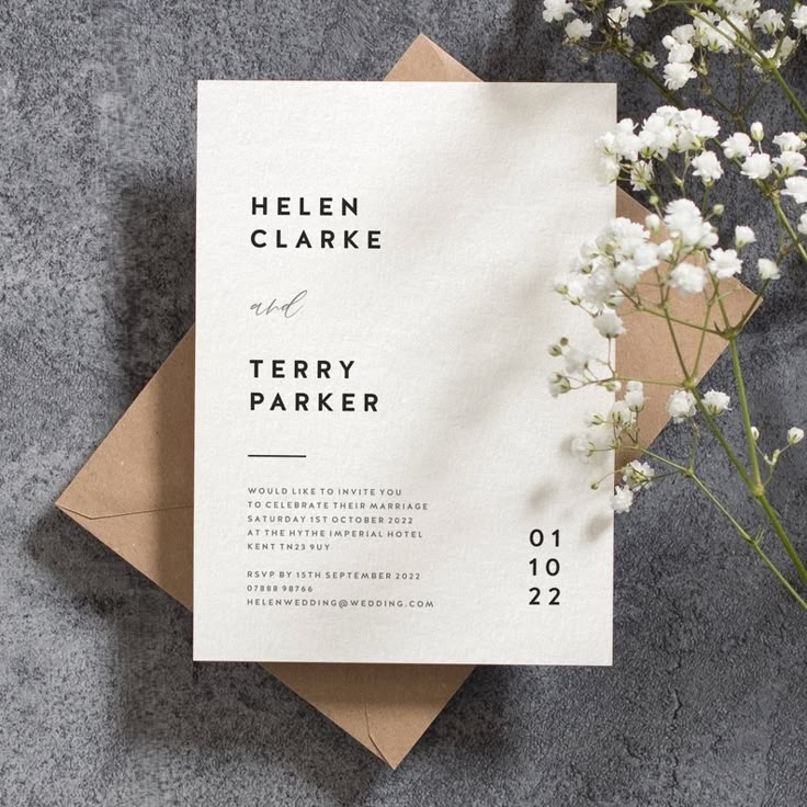 the wedding stationery is laid out on top of an envelope and some white flowers