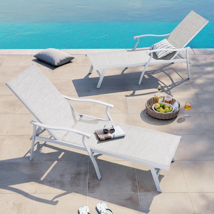 two lounge chairs sitting next to each other near a pool