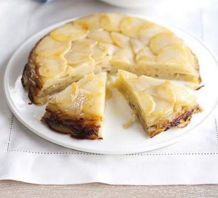 a white plate topped with a cake covered in sliced bananas on top of a table