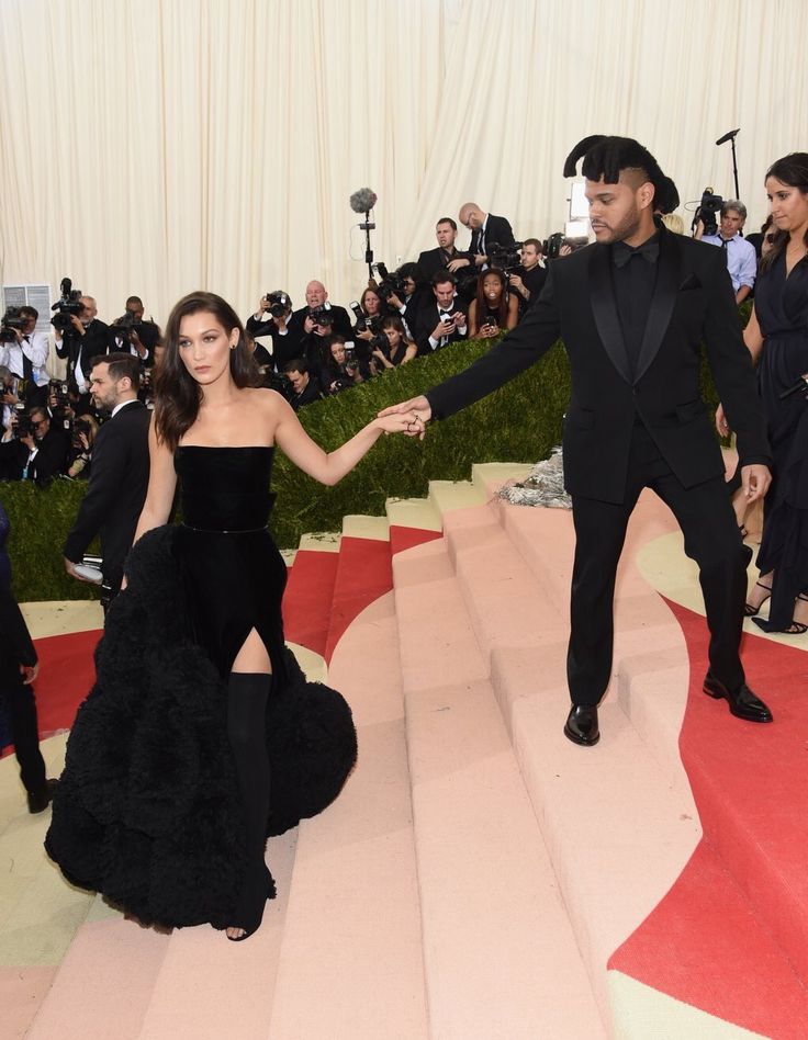 a man and woman in formal wear walking down the red carpet with their arms around each other