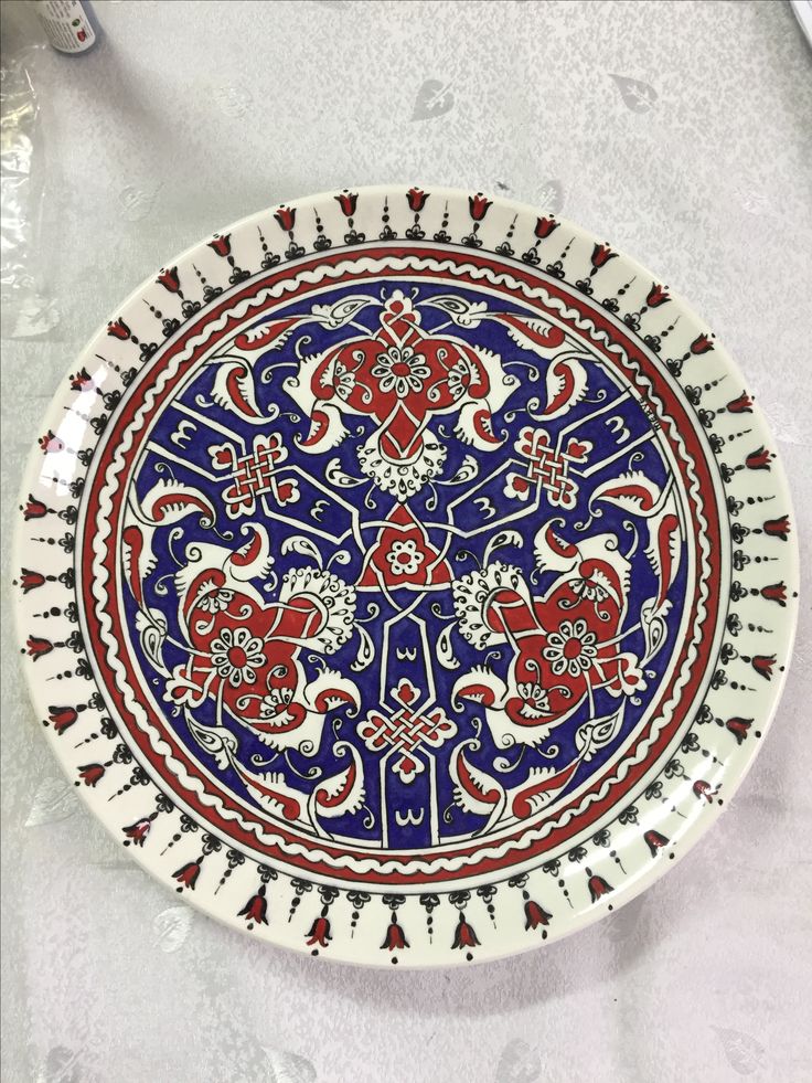 a blue and red plate sitting on top of a white tablecloth next to utensils