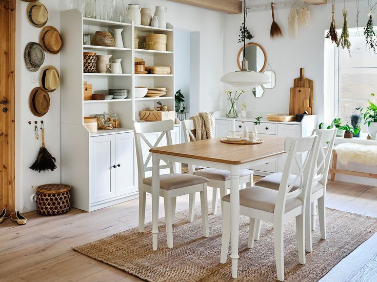 a dining room table with white chairs and wooden shelves