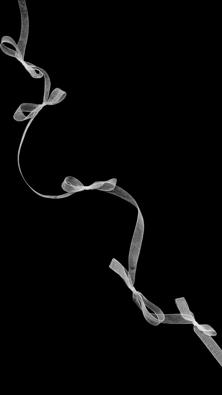 a black and white photo of a ribbon on a black background with the word love spelled below it