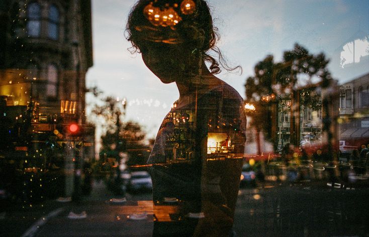 the reflection of a woman's head in a glass window on a city street